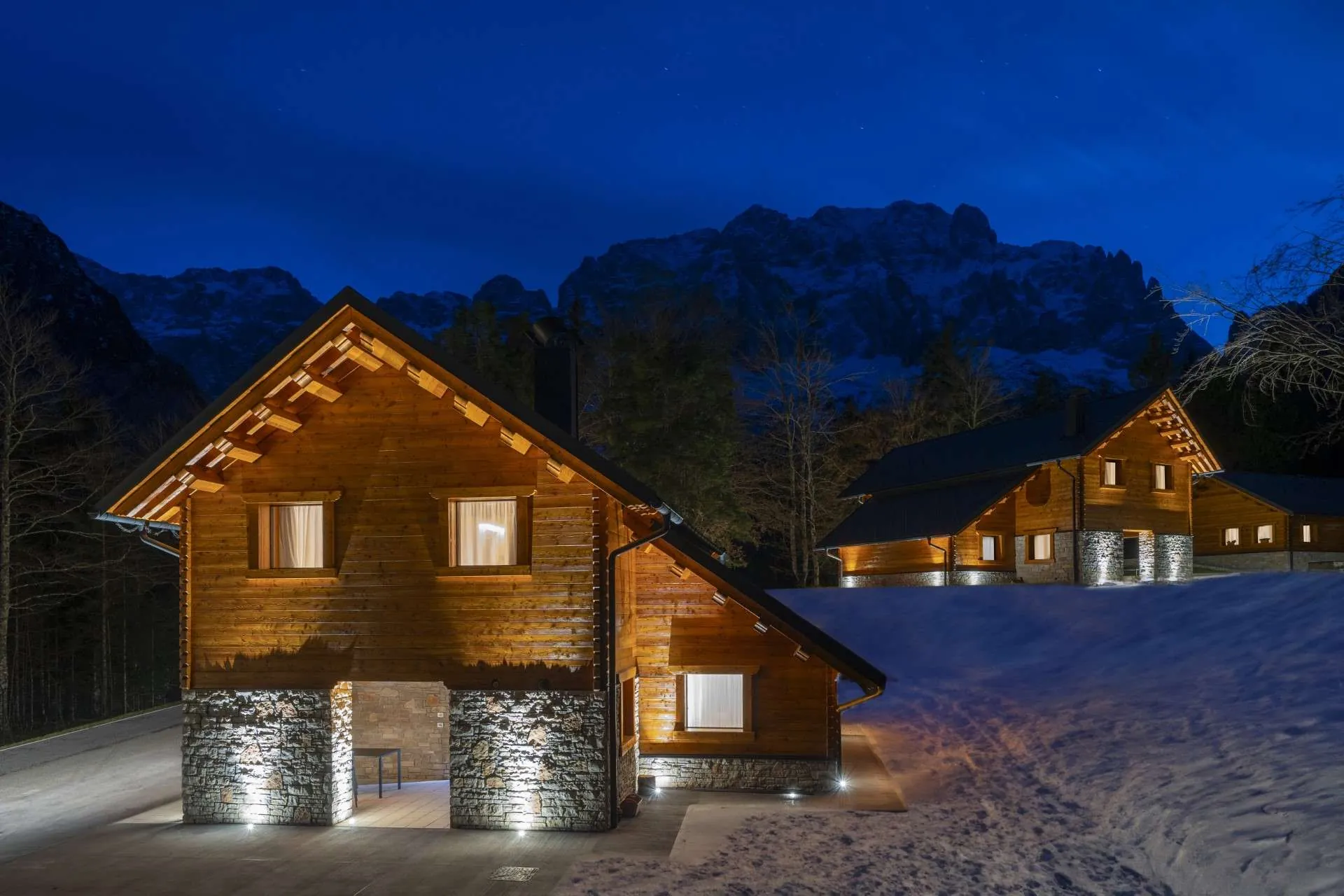 Uno degli chalet del Kile Alpine Resort di notte, con le pareti del Montasio dietro
